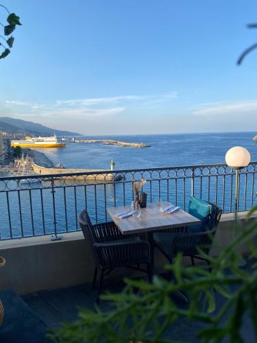 a table on a balcony with a view of the ocean at Hôtel Des Gouverneurs in Bastia