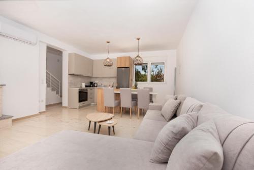 a white living room with a couch and a kitchen at Elegant Villa - Private Pool, Heated Jacuzzi & Sea Breeze in Chanioti, Chalkidiki in Hanioti