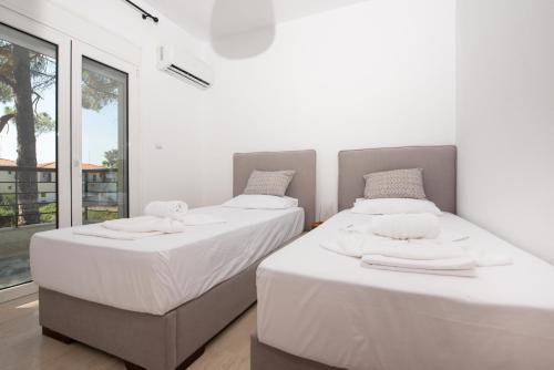 two twin beds in a room with a window at Brand new maisonette in Chanioti, Chalkidiki in Hanioti