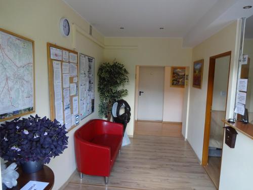 a room with a red chair and maps on the wall at MADOHORA_SŁOŃCE in Zaryte