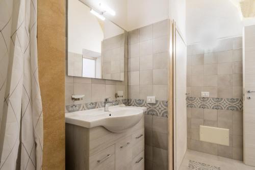 een badkamer met een wastafel, een spiegel en een douche bij Casa Emi by BarbarHouse in Veglie