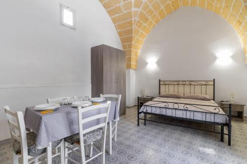 een slaapkamer met een bed en een tafel en stoelen bij Casa Emi by BarbarHouse in Veglie