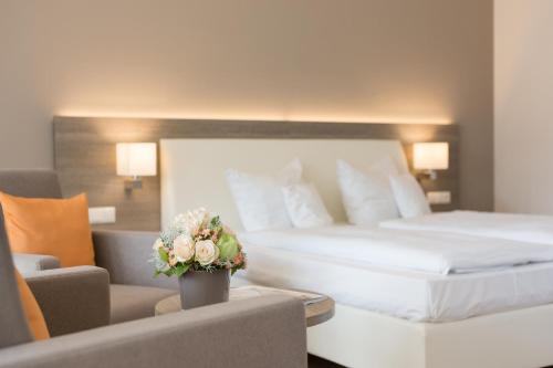 a hotel room with two beds and a couch and flowers at HerzogsPark Apartments mit oder ohne Küche in Herzogenaurach