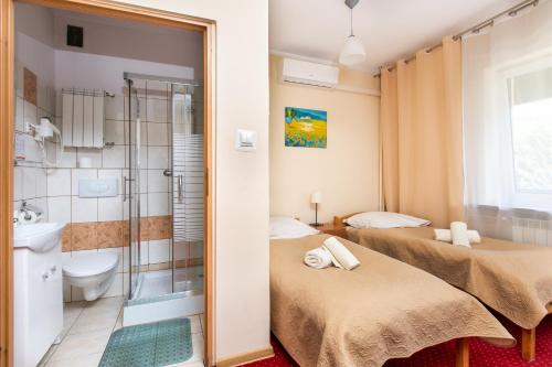 two beds in a room with a shower and a bathroom at MADOHORA_SŁOŃCE in Zaryte