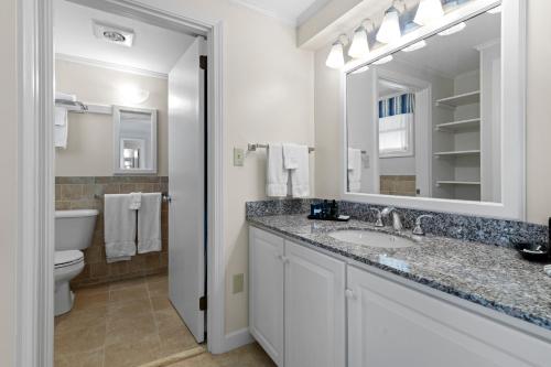 W łazience znajduje się umywalka, toaleta i lustro. w obiekcie The Sparhawk Oceanfront Resort w mieście Ogunquit
