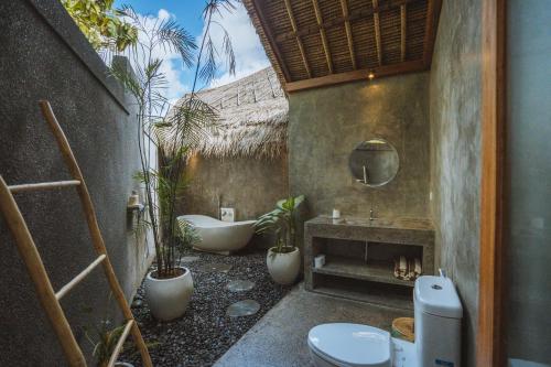 a bathroom with a tub and a toilet and a sink at Villa Amantes Bingin in Uluwatu