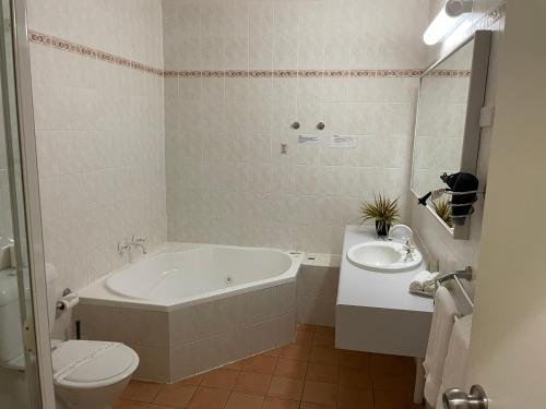 a bathroom with a tub and a toilet and a sink at Lakeview Motor Inn in Belmont