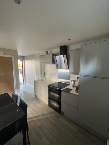 uma cozinha com armários brancos e um fogão preto em The Annexe, Farnborough em Farnborough