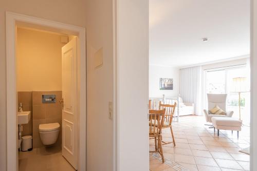 a living room with a toilet and a table and chairs at Domizil Strandpartie in Wenningstedt
