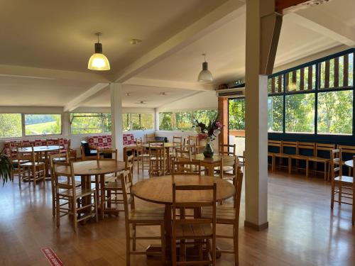un restaurant avec des tables et des chaises en bois ainsi que des fenêtres dans l'établissement ULVF Les Essertets, à Praz-sur-Arly