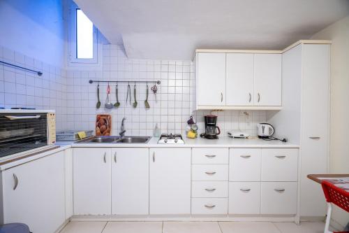 una cucina bianca con armadi bianchi e lavandino di Independent Apartment at Lykavitos 1 bed 2 pers ad Atene