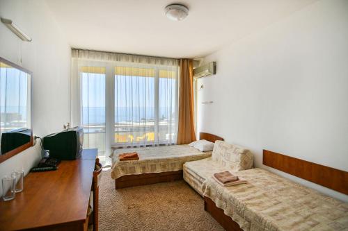 a room with a bed and a desk and a television at International Home of Scientists Joliot Curie in Saints Constantine and Helena