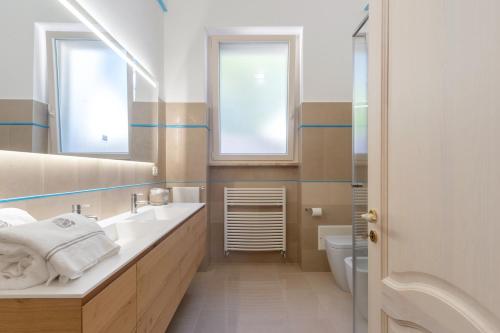 a bathroom with a sink and a toilet and two windows at VILLA ROSA MEDITERRANEA in Marina di Pescoluse