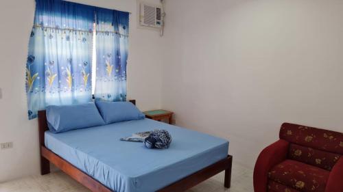 a bedroom with a blue bed and a red chair at Babas Guesthouse in Moalboal