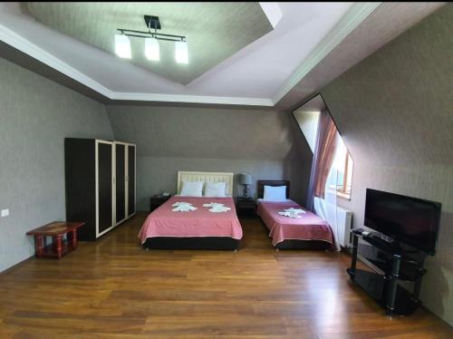 a bedroom with two beds and a flat screen tv at Hotel Rich in Tbilisi City