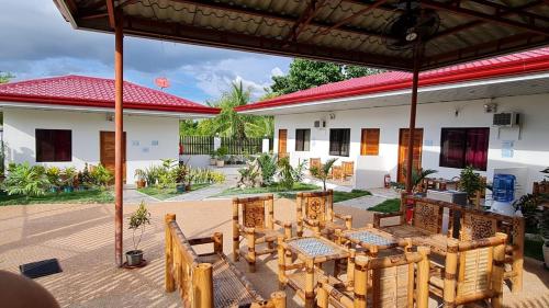 een patio met houten tafels en stoelen voor een huis bij Babas Guesthouse in Moalboal