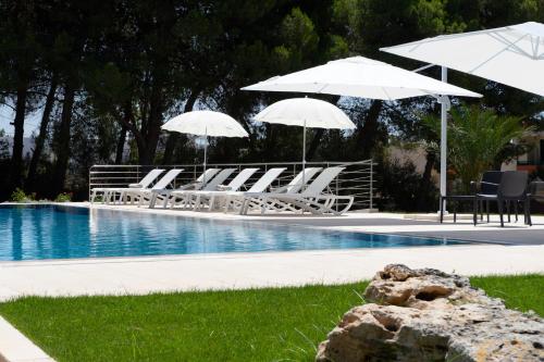 a group of chairs and umbrellas next to a pool at VILLA ROSA MEDITERRANEA in Marina di Pescoluse