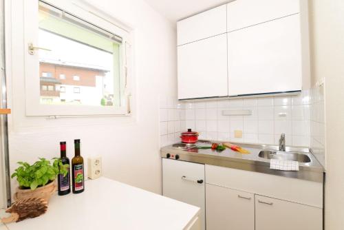 a white kitchen with bottles of wine on a counter at Familienhotel Kleinwalsertal in Riezlern