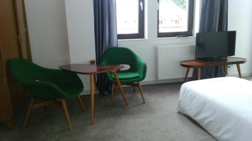 a room with two chairs and a table and a television at Willa Uroboros in Szklarska Poręba