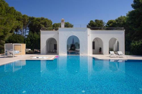 a swimming pool with blue water in front of a house at VILLA ROSA MEDITERRANEA in Marina di Pescoluse