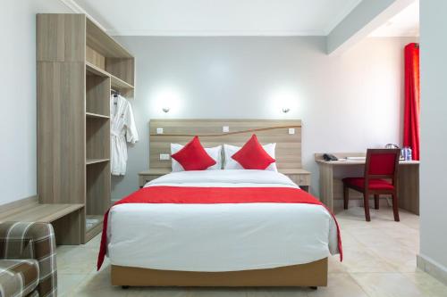 a bedroom with a bed with red pillows and a desk at Rock Hyrax Hotel in Nakuru