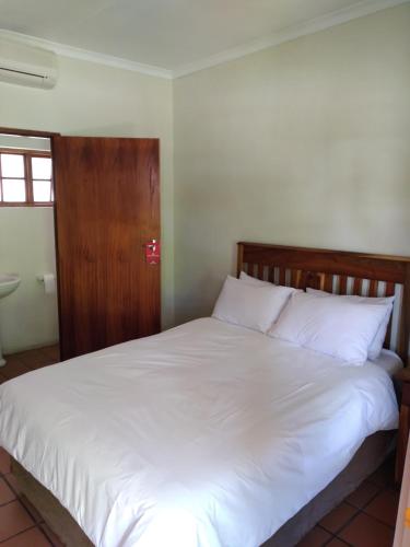 a bed with white sheets and a wooden headboard at Kuruman Hotel in Kuruman
