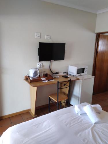 a bedroom with a desk with a tv and a bed at Kuruman Hotel in Kuruman