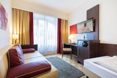 a hotel room with a bed and a desk at ACHAT Sternhotel Bonn in Bonn