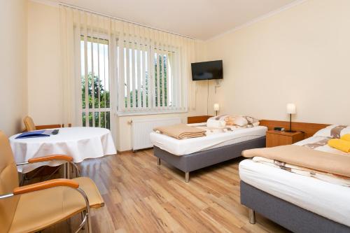 um quarto com três camas e uma mesa e uma janela em MADOHORA ŚLEMIEŃ em Kocoń