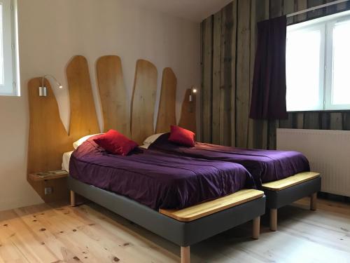 Schlafzimmer mit einem Bett mit lila Bettwäsche und roten Kissen in der Unterkunft Village Vacances - DéfiPlanet' in Dienné