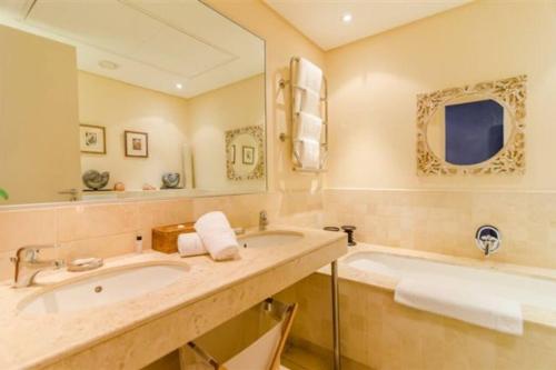 y baño con 2 lavabos, bañera y espejo. en Parama 003 Secure, Luxurious Waterfront Apartment en Ciudad del Cabo