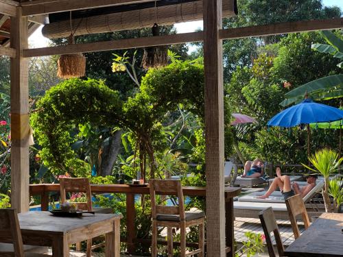 a patio with tables and chairs and people in the garden at Le Biu garden View in Nusa Lembongan