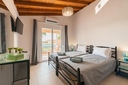 a bedroom with two beds and a balcony at CASA OLIVE GENNADI in Gennadi