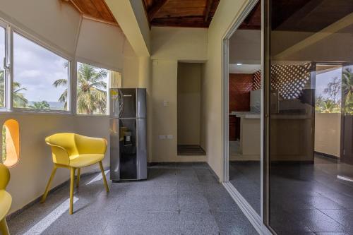 a yellow chair in a room with a refrigerator at Hotel Turístico Marian in Las Terrenas