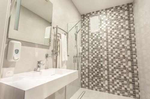 a white bathroom with a sink and a shower at Optima Collection Khmelnytskyi in Khmelʼnytsʼkyy