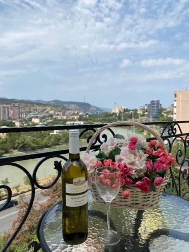 a bottle of wine sitting on a table with a basket of flowers at Hotel RichI G A in Tbilisi City