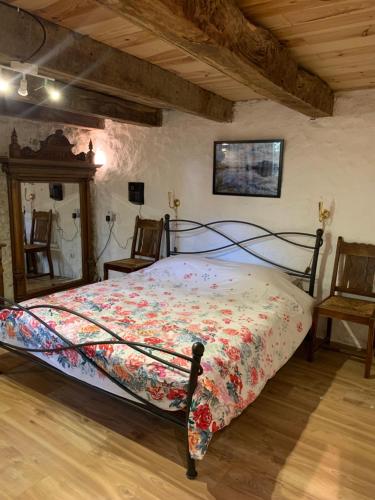 a bedroom with a bed with a floral bedspread and two chairs at Petite maison Conjat in Saint-Julien-le-Petit