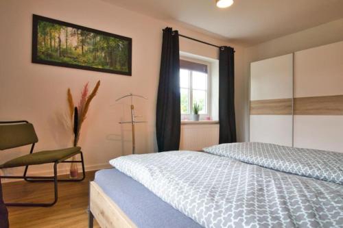 a bedroom with a bed and a chair and a window at Ferienhaus Haas - Am Heidschnuckenweg in Faßberg