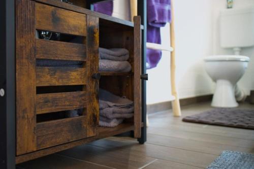 un armario de madera con toallas plegadas en el baño en Ferienhaus Haas - Am Heidschnuckenweg, en Faßberg