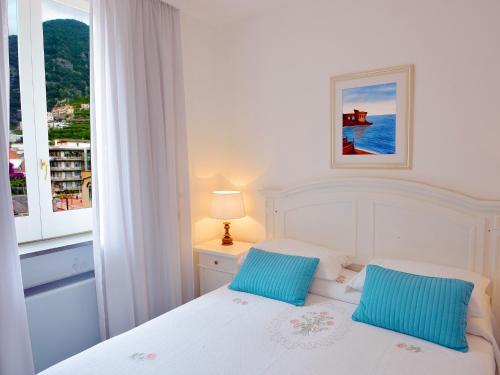 a white bed with two blue pillows in a bedroom at Torre Paradiso in Minori