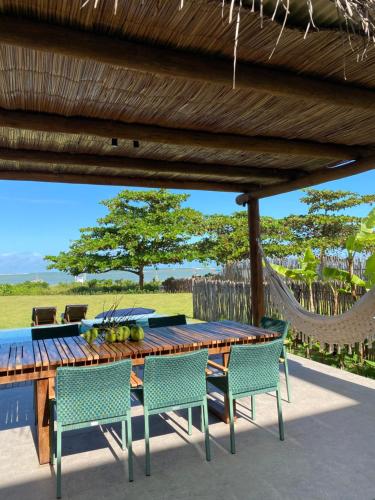 a wooden table and chairs on a patio with a hammock at Casa Playa Milagres in São Miguel dos Milagres