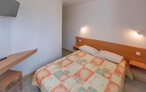 a bedroom with a bed and a television in it at Les Aliziers in Super Besse