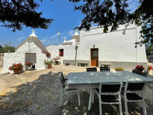 stół i krzesła przed białym budynkiem w obiekcie Trulli Demetra w mieście Martina Franca