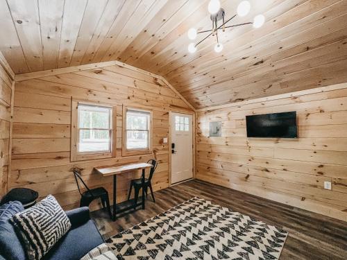 Cabaña de madera con mesa y TV en Cabin #10 One Bedroom W Kitchenette, en Hartwell