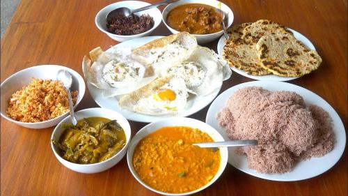 a table topped with bowls of different types of food at Paradise inn in Kamburagalla