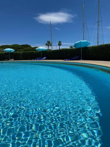 una piscina azul con sillas y sombrillas en Magnifique 2 pièces vue port et mer en Cogolin