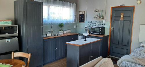 a kitchen with blue cabinets and a table in it at Mrs Catherines Selfcatering Apartment in George