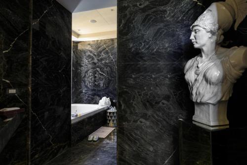 a bathroom with a statue of a woman on the wall at Grand Hotel Des Etrangers in Siracusa