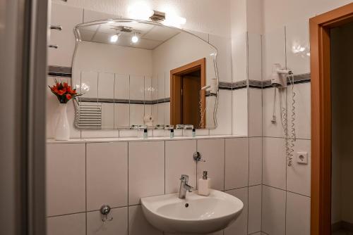 a white bathroom with a sink and a mirror at Hotel Fruerlund in Flensburg