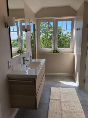 ein Badezimmer mit einem Waschbecken und einem großen Spiegel in der Unterkunft Gästehaus Muhl in Strukkamp auf Fehmarn